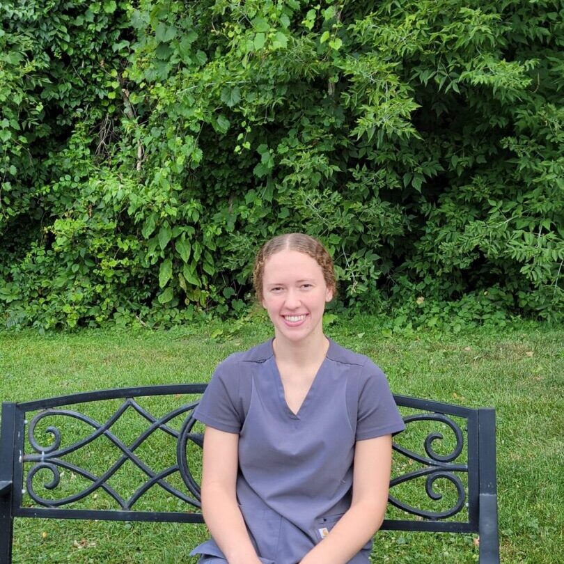 Smiling veterinary technician in gray scrubs outdoors